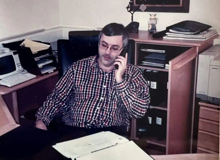 a man sitting at a desk talking on a phone